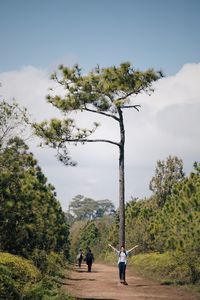 Full length of woman with arms outstretched standing by tree at phu kradueng national park