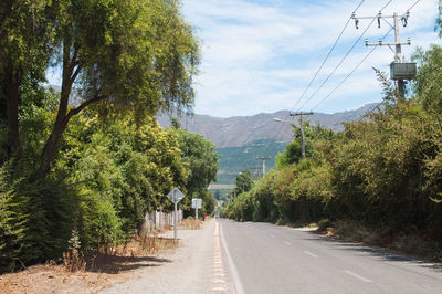 Road amidst trees and mountains against sky