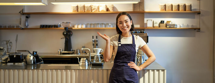 Portrait of young woman standing in kitchen