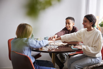 Girl and boys playing scrabble at dining table