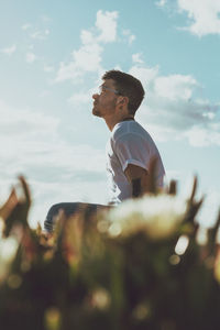 Side view of man on rock against sky