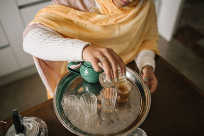 Close-up of woman pouring tea in cup at home