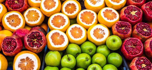 Sales stand for juice of apples, oranges and pomegranates with sliced fruits