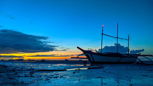 Sailboat moored on sea against blue sky