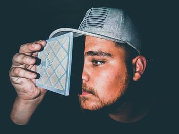 Portrait of man holding camera over black background