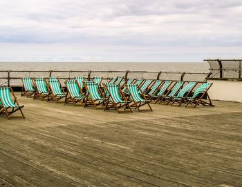 Chairs on sand at beach against sky