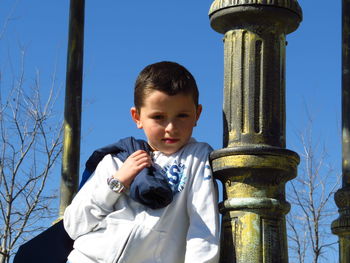 Portrait of boy standing against blue sky