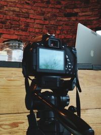 Close-up of camera on table against brick wall