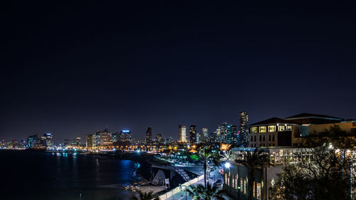 Illuminated cityscape against clear sky at night