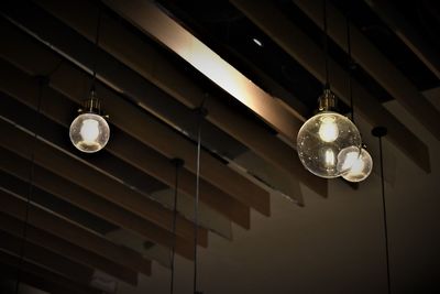 Low angle view of illuminated light bulbs hanging from ceiling