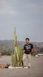 Portrait of smiling man standing by plant against sky