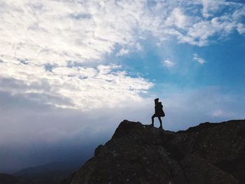 Man standing on rock against sky