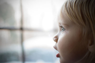 Profile view of baby girl looking through window