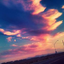 Scenic view of landscape against cloudy sky at sunset