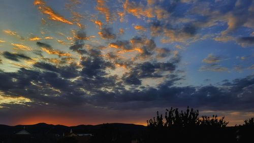 Silhouette trees against dramatic sky during sunset