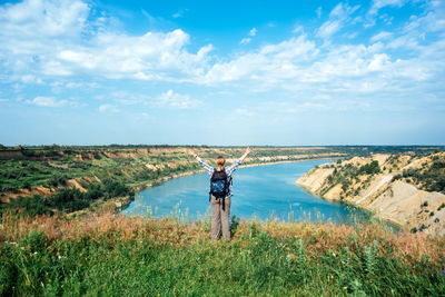 Rear view of woman walking on field against sky