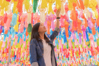 Smiling woman standing against multi colored paper lanterns