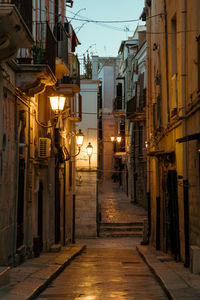 Narrow alley amidst buildings in city at night