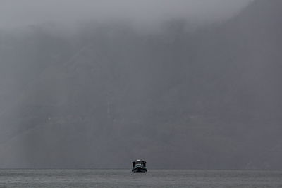 Boat on sea against mountain