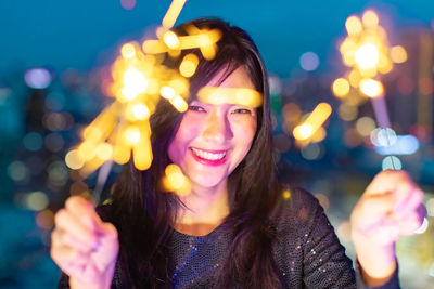 Portrait of smiling young woman holding sparkler