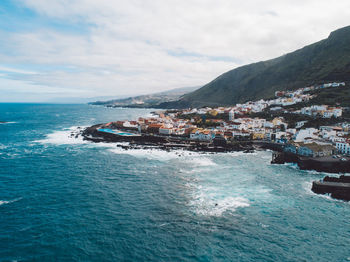 Scenic view of sea by buildings against sky