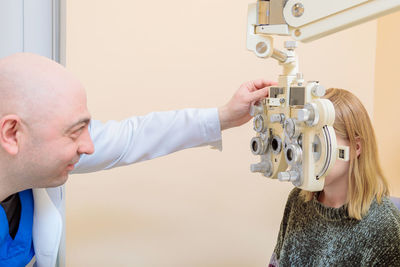 A male ophthalmologist checks a girl's eyesight using a phoropter. vision treatment