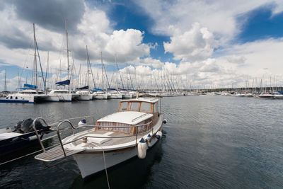 Sailboats moored at harbor against sky