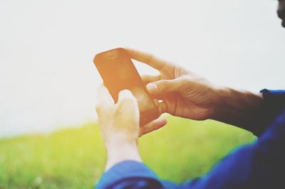 Close-up of hands using smart phone against lake