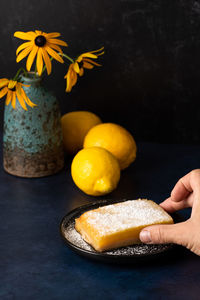 Close-up of hand holding yellow flowers on table