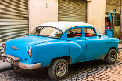 Old vintage car on street against buildings