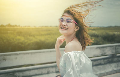 Portrait of smiling young woman standing on field