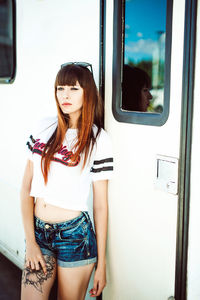 Young woman standing by camper trailer