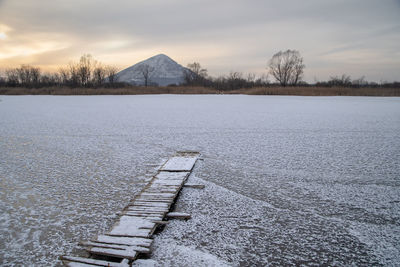 Scenic view of lake by snowcapped mountain against sky