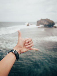 Cropped hand gesturing against sea