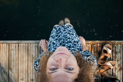 Directly above shot of woman sitting on pier over lake