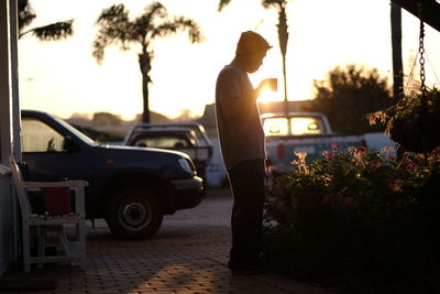 Man standing on street against sky during sunset