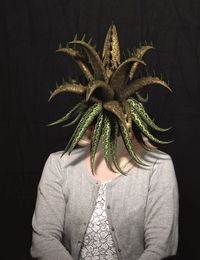 Close-up of person holding leaf against black background