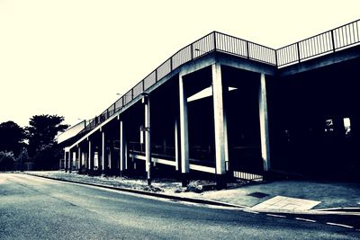 Empty road by building against clear sky