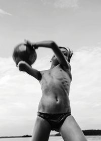 Low angle view of shirtless man standing against sky