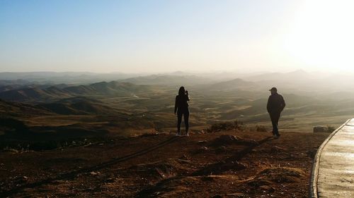 People standing on mountain against clear sky