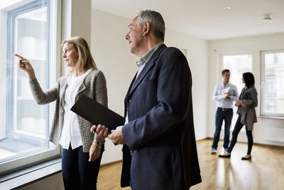 Real estate agents discussing while couple standing in background at new home