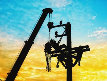 Silhouette electrical engineers working on electricity pylon high tension power line repairs