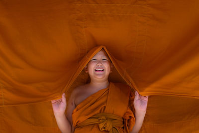 Portrait of happy boy wearing traditional clothing holding orange textile