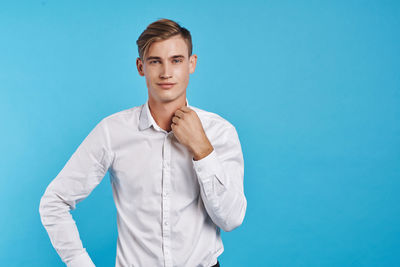 Portrait of young man standing against blue background