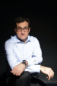 Mid adult man sitting against black background