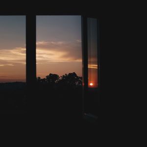 Silhouette trees against sky during sunset seen through window