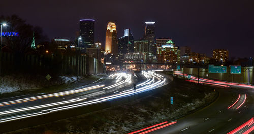 High angle view of light trails on road amidst buildings at night