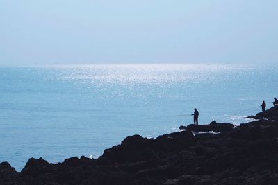 Silhouette people on beach against sky