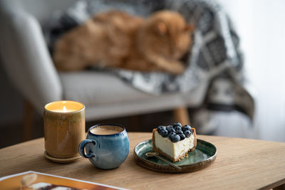 Slice of blueberry cheesecake and a cup of coffee on the coffee table. cozy scandinavian interior