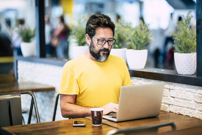 Mature man using laptop on table while sitting in cafe